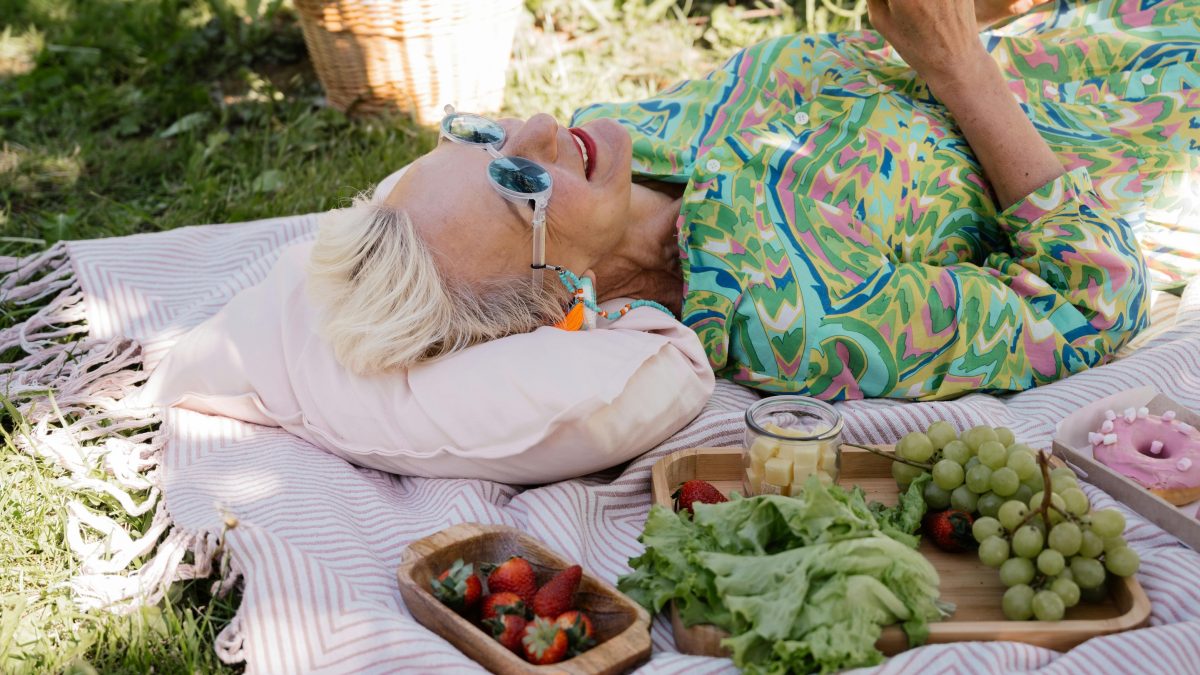Woman over 40 enjoying a peaceful garden picnic, embracing self-acceptance, life balance, and letting go of stress.
